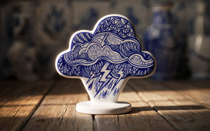 Blue and white ceramic cloud figurine decorated with storm patterns, lightning bolts, and raindrops on a wooden surface.