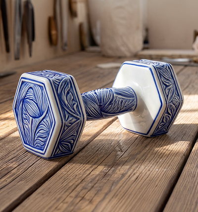 Blue and white ceramic dumbbell on a wooden surface.